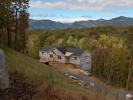 A home being built on the side of a mountain at the start of fall