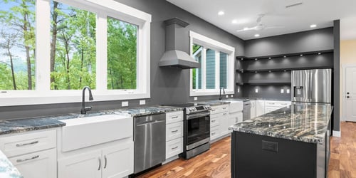 A custom kitchen with all the cabinets and appliances, painted dark grey but in a well lit room