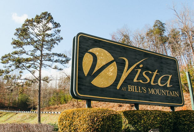 The Vista Developers at Bill's Mountain sign in a woodsy area.