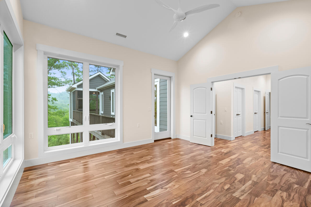 A spare bedroom in a newly built custom home, overlooking the trees in a mountainous landscape.